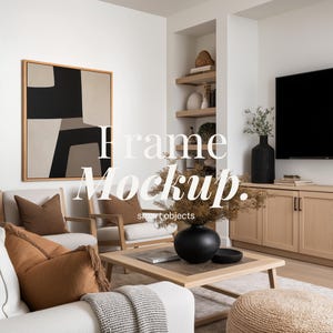 May include: A modern living room with neutral tones. A large framed abstract art piece hangs above a white sofa with brown pillows. A wooden coffee table and a black vase with dried flowers are in the center. The text "Frame Mockup" is visible.