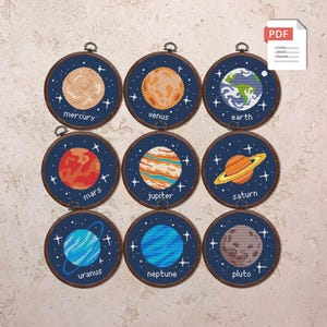 Puede incluir: Nueve patrones redondos de punto de cruz de planetas, cada uno en un aro azul oscuro. Los planetas incluyen Mercurio, Venus, Tierra, Marte, Júpiter, Saturno, Urano, Neptuno y Plutón. Cada planeta está etiquetado con su nombre en texto blanco, con un icono PDF.