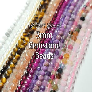 May include: A variety of 3mm gemstone beads in shades of white, brown, orange, red, purple, and pink. The image includes the text "Desert Bloom 3mm Gemstone Beads". The beads are strung together, showcasing their faceted surfaces and diverse colors.