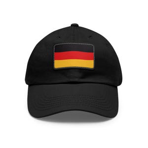Könnte beinhalten: Schwarze Baseballkappe mit einem rechteckigen Aufnäher mit der deutschen Flagge: schwarze, rote und gelbe horizontale Streifen. Die Kappe hat einen gebogenen Schirm.