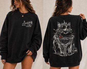 May include: Black sweatshirt with a graphic of a cat wearing sunglasses and a crown, holding a cocktail with a cherry. The front of the sweatshirt has the text "The Desperado Club" in white.