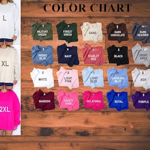 May include: A color chart displays various sweatshirt colors, including Military Green, Navy, and Scarlet Red. The chart also shows the sizes L, XL, and 2XL. The sweatshirts are displayed on a wooden background.