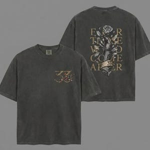 以下が含まれることがあります： チャコールグレーのTシャツ2枚。1枚のシャツには、前面に装飾要素が付いた数字「33」が表示されています。もう1枚のシャツには、バラを持った手と「For Those Who Come After」というテキストと数字「33」が表示されています。