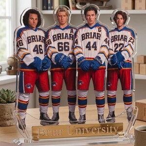 Op de afbeelding: Acryl display met vier figuren in hockeytruien. De truien zijn wit met blauwe en gouden strepen, en de tekst "Briar" en nummers zijn zichtbaar. De figuren staan op een voet met "Briar University" gegraveerd.