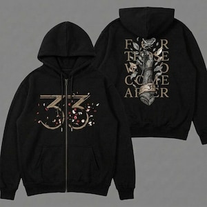 May include: Black zip-up hoodie with a hood and front pockets. The front features the number "33" in a gold colour with scattered confetti. The back displays a floral design with the text "FOR THOSE WHO COME AFTER".