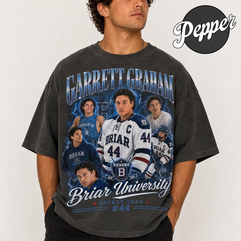 May include: Dark gray t-shirt featuring a graphic of Garrett Graham, Briar University hockey player. The design includes the text "Garrett Graham", "Briar University Hockey Team", and the number "44". The shirt has a vintage, distressed look.
