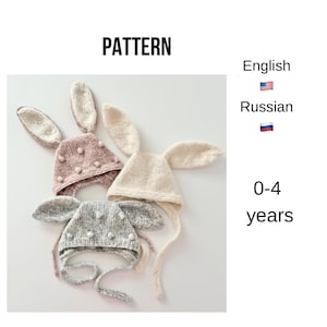May include: Three knitted bunny hats in pink, cream, and gray, each with long, floppy ears and pom-pom details. The hats have ties under the chin. The word "PATTERN" is at the top, and "0-4 years" is written below the hats.