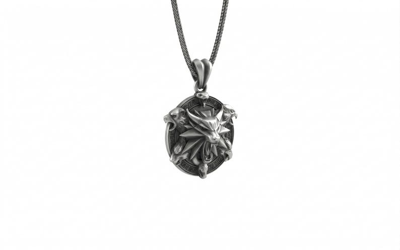 May include: Silver-toned pendant necklace featuring a detailed oval pendant with a wolf's head emblem and three stylized animal heads. The pendant hangs from a matching chain, creating a striking accessory. The design is set against a white background.