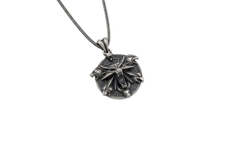 May include: Silver-toned pendant necklace featuring a circular pendant with a detailed, stylized wolf's head and other animal figures. The pendant is suspended from a matching chain. The design has a fantasy or medieval theme.