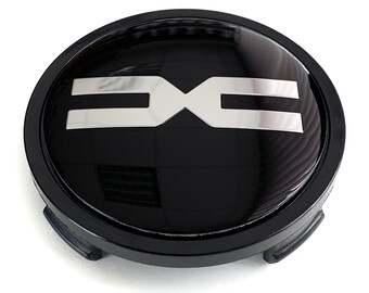 May include: A black and silver car wheel center cap with a glossy finish. The cap features a silver emblem in the center, with the letters "DXC" in a bold, stylized font. The cap has a circular shape with a black outer ring.