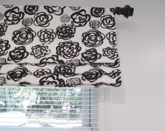 Puede incluir: Una cortina romana blanca con un patrón floral en blanco y negro. La cortina está montada sobre una ventana con persianas blancas.