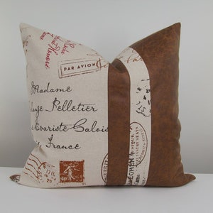 May include: A decorative pillow with a brown faux leather back and a front made of beige fabric with a vintage French postage stamp design. The fabric features the text "PAR AVION", "Madame", "Laje Pelletier", "Evariste Balois", and "France".