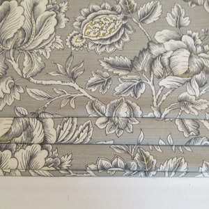 May include: Gray fabric with a white and black floral pattern. The fabric is pleated and has a subtle sheen.