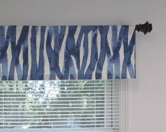 May include: A white and blue patterned valance with a blue and white abstract design. The valance is hung on a brown curtain rod.