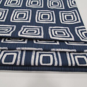 May include: A stack of blue fabric with a white geometric pattern of squares. The fabric has a textured surface.