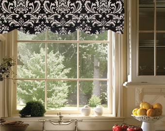 May include: A black and white damask patterned roman shade with scalloped edges hangs above a window with a view of trees. The window is in a kitchen with a white countertop, a stainless steel sink, and a bowl of fruit on a pedestal.