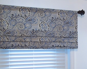 May include: A blue and white patterned roman shade with a decorative finial on the rod.