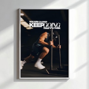 Puede incluir: Impresión enmarcada que muestra a una persona empujando un trineo con peso en un gimnasio. La imagen incluye el texto "YOU ARE CLOSER THAN YOU THINK KEEP GOING" en blanco. La persona viste ropa deportiva y una gorra.