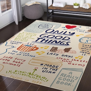 May include: A rectangular area rug with a cream-colored background and colorful illustrations. The rug features the phrase "ONLY GOOD THINGS" in large blue letters, along with other handwritten phrases and drawings, including a coffee cup and musical notes. The rug is labeled "#MADE IN THE USA".