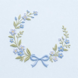 May include: An embroidery design featuring a semi-circular wreath of light blue five-petaled flowers with yellow centers, accented by sage green leaves and stems, finished with a light blue ribbon bow at the bottom center on a light blue fabric.