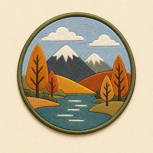 Puede incluir: Un parche bordado circular que presenta un paisaje con un río azul, colinas de color amarillo dorado y árboles de otoño naranjas. Al fondo, dos montañas azul oscuro con picos nevados blancos se alzan bajo un cielo azul claro con nubes blancas.