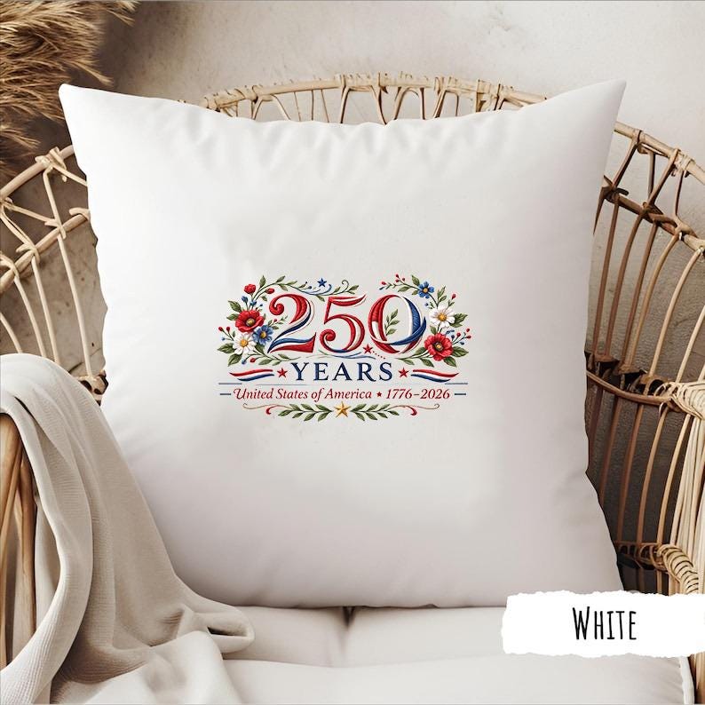 May include: White square pillow with a patriotic design celebrating 250 years of the United States of America. The design includes the text "250 YEARS" with red, white, and blue floral accents and the years 1776-2026.