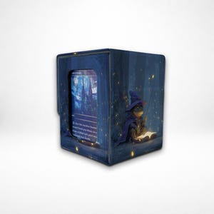 May include: A navy blue card storage box with a whimsical illustration of a frog wizard reading a book in a forest. The box has a card visible in a window. The frog is wearing a purple hat and cloak.