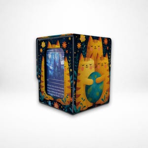May include: A card storage box featuring a whimsical design with orange cats and a blue and green globe. The box has a dark blue background with floral accents and a card visible on the front.