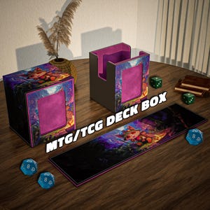 Puede incluir: Un juego de cajas de cartas MTG/TCG con una alfombrilla a juego. Las cajas son negras con un diseño de arte fantástico colorido y un interior rosa. La alfombrilla presenta el mismo diseño. Dados y un pequeño libro también están sobre la superficie de madera.