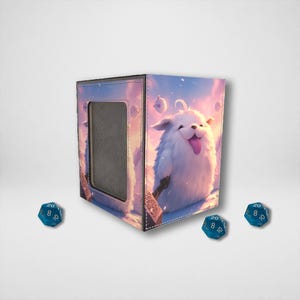 May include: A square, fabric dice box with a cartoon illustration of a white, fluffy creature with its tongue out. The box has a rectangular opening and is surrounded by three blue, twenty-sided dice.
