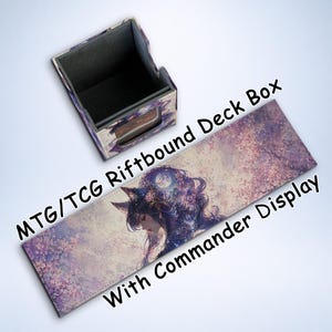 May include: A deck box and playmat set for MTG/TCG games. The box is rectangular with a purple and white floral design. The playmat features a fantasy illustration of a woman with wolf ears and the text "MTG/TCG Riftbound Deck Box With Commander Display."