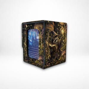 Könnte beinhalten: Eine rechteckige Deckbox mit einer Fantasy-Illustration eines Waschbären-Zauberers in einem Wald mit Pilzen und leuchtenden Lichtern. Die Vorderseite hat ein Sichtfenster, in dem eine blaue Sammelkarte mit Text zu sehen ist.