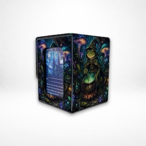 May include: A rectangular deck box featuring a vibrant fantasy illustration of a frog wizard in a pointed hat stirring a glowing green cauldron. The box has a clear window on the front displaying a blue trading card with visible text.