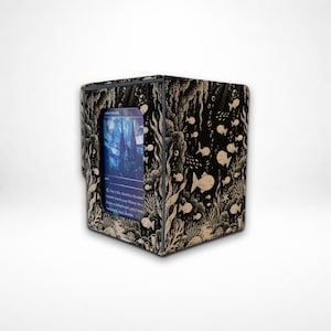 May include: A black and beige deck box featuring an intricate underwater illustration of coral, seaweed, and various fish. A rectangular window on the front displays a blue trading card with a stained-glass style building illustration.