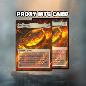 Könnte beinhalten: Zwei "The One Ring" Proxy-MTG-Karten. Die Karten zeigen ein goldenes Ringdesign mit feurigen Orange- und Gelbtönen. Der Text "PROXY MTG CARD" steht oben. Die Karten sind mit "Legendary Artifact" beschriftet und enthalten Spieltext.