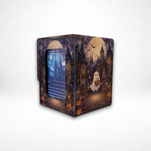 May include: A rectangular deck box featuring a Halloween-themed illustration of a ghost holding a basket in a spooky village with a full moon, bats, and jack-o'-lanterns. A trading card with blue stained-glass artwork is visible in the front window.