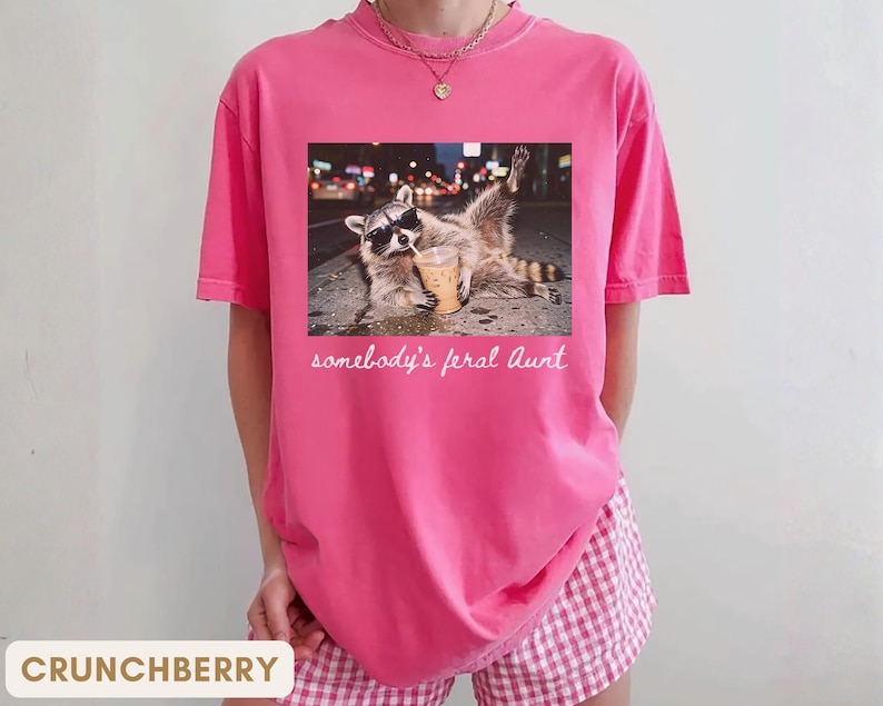 crunchberry funny aunt shirt with raccoon drinking iced coffee, somebody’s feral aunt graphic tee, cute pregnancy reveal gift for cool auntie