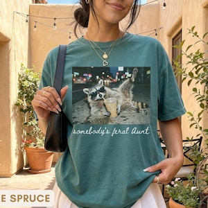 blue spruce funny aunt shirt with raccoon graphic, promoted to aunt pregnancy reveal shirt, stylish and modern aunt gift