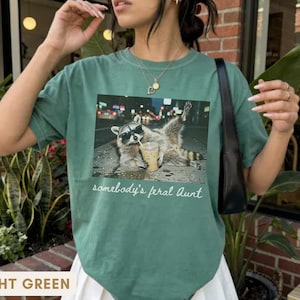 light green raccoon meme shirt for aunt, funny somebody’s feral aunt tee with iced coffee design, unique gift for new aunt