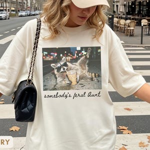 ivory raccoon meme shirt for aunt, funny somebody’s feral aunt tee with iced coffee design, unique gift for new aunt