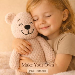 May include: A light pink crocheted teddy bear with a black nose and smiling mouth is being hugged. The text "Make Your Own" and "PDF Pattern" are displayed on the image.