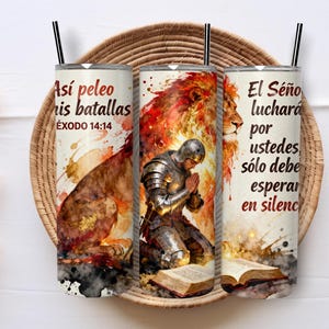 May include: Three stainless steel tumblers with black straws, each with a watercolour design. The design includes a lion, a praying knight, and Spanish text. The tumblers are displayed on a woven tray.