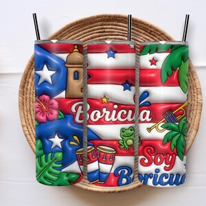 Può includere: Tre bicchieri in acciaio inossidabile con cannucce nere, con un design vibrante con la bandiera portoricana, il testo "Boricua" e altri simboli culturali. I bicchieri sono esposti in un cesto intrecciato.