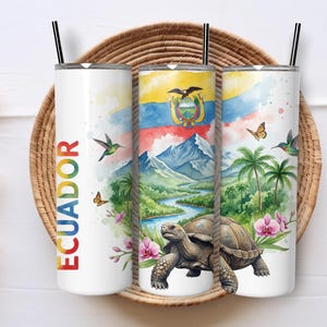 Peut inclure: Gobelet blanc avec un motif aquarelle du drapeau de l'Équateur, des montagnes et une tortue. Le mot "ECUADOR" est imprimé verticalement en couleurs arc-en-ciel. Comprend une paille noire.