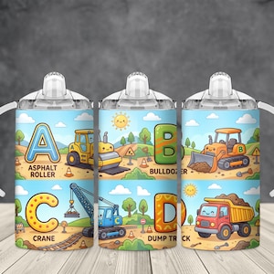 May include: Three sippy cups with white handles and lids. Each cup features a colorful illustration of construction vehicles with the letters A, B, C, and D. The text includes "Asphalt Roller", "Bulldozer", "Crane", and "Dump Truck".