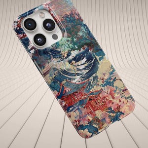 May include: A colorful phone case with a vibrant abstract design. The case features a mix of blue, red, pink, and white hues, creating a painterly effect. The case has a camera cutout with three lenses.