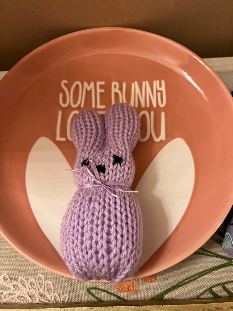 May include: A purple knitted bunny rabbit on a pink plate with the text "Some bunny loves you".