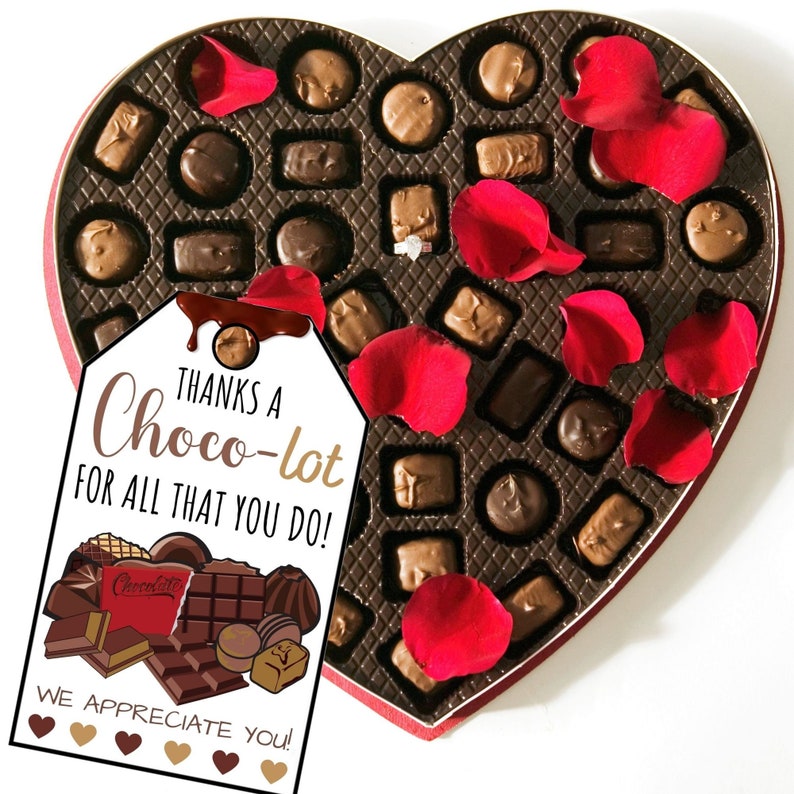 May include: A heart-shaped box filled with assorted chocolates, decorated with red rose petals. A tag attached to the box reads "Thanks a Choco-lot for all that you do!" with a chocolate bar illustration and the text "We appreciate you!"