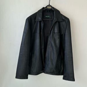 May include: A black leather jacket with a classic collar, a full-length front zipper, and two side pockets. The jacket features a horizontal seam across the chest and a small zippered pocket on the left side. A label reading Springfield is visible.