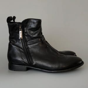 May include: A pair of black leather ankle boots. The boots have a side zipper with a silver-tone pull and a low heel. The leather appears slightly distressed, giving the boots a worn-in look. The boots are designed for everyday wear.